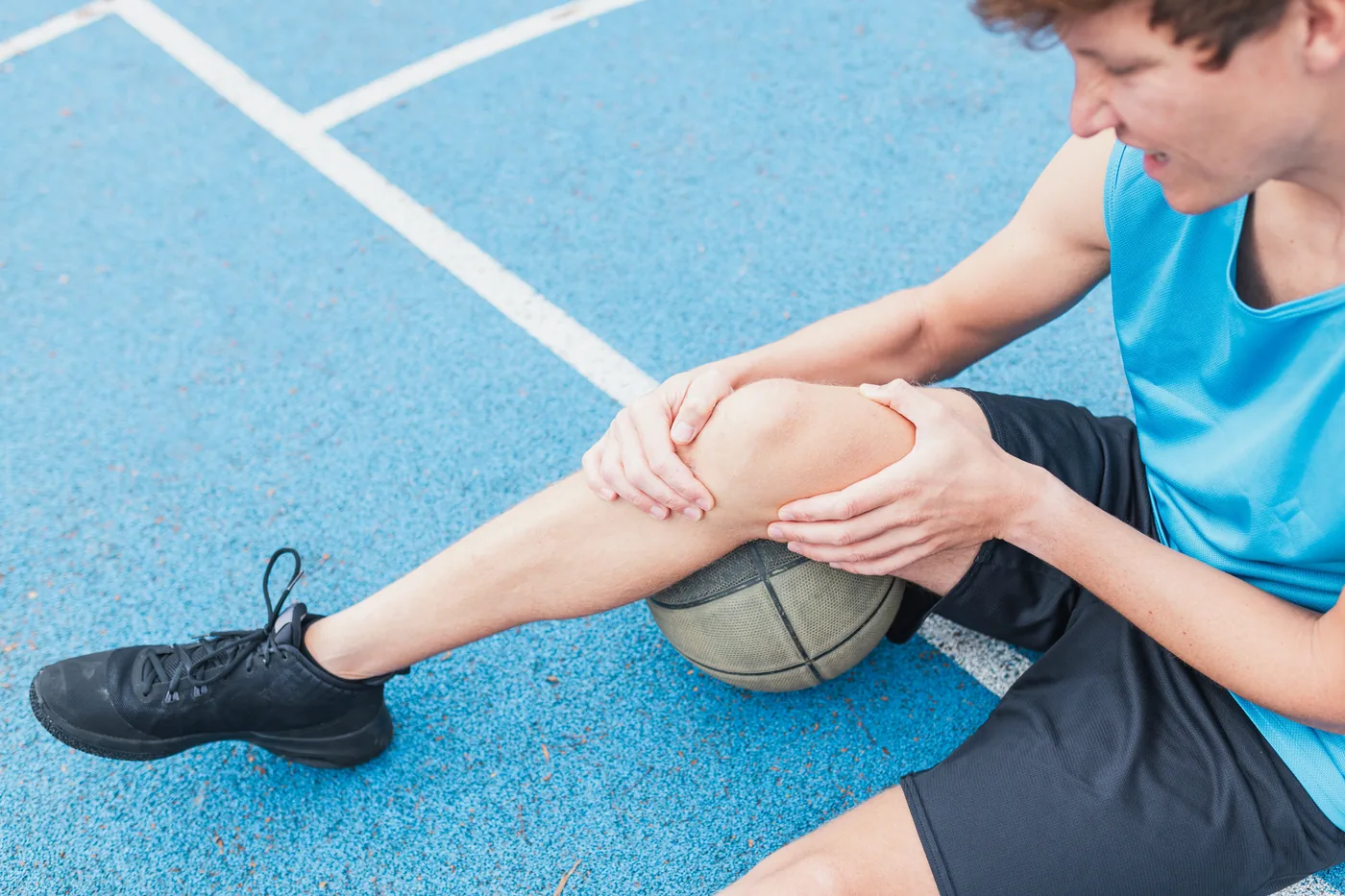 Basketball player holding his knee on the court after an injury
