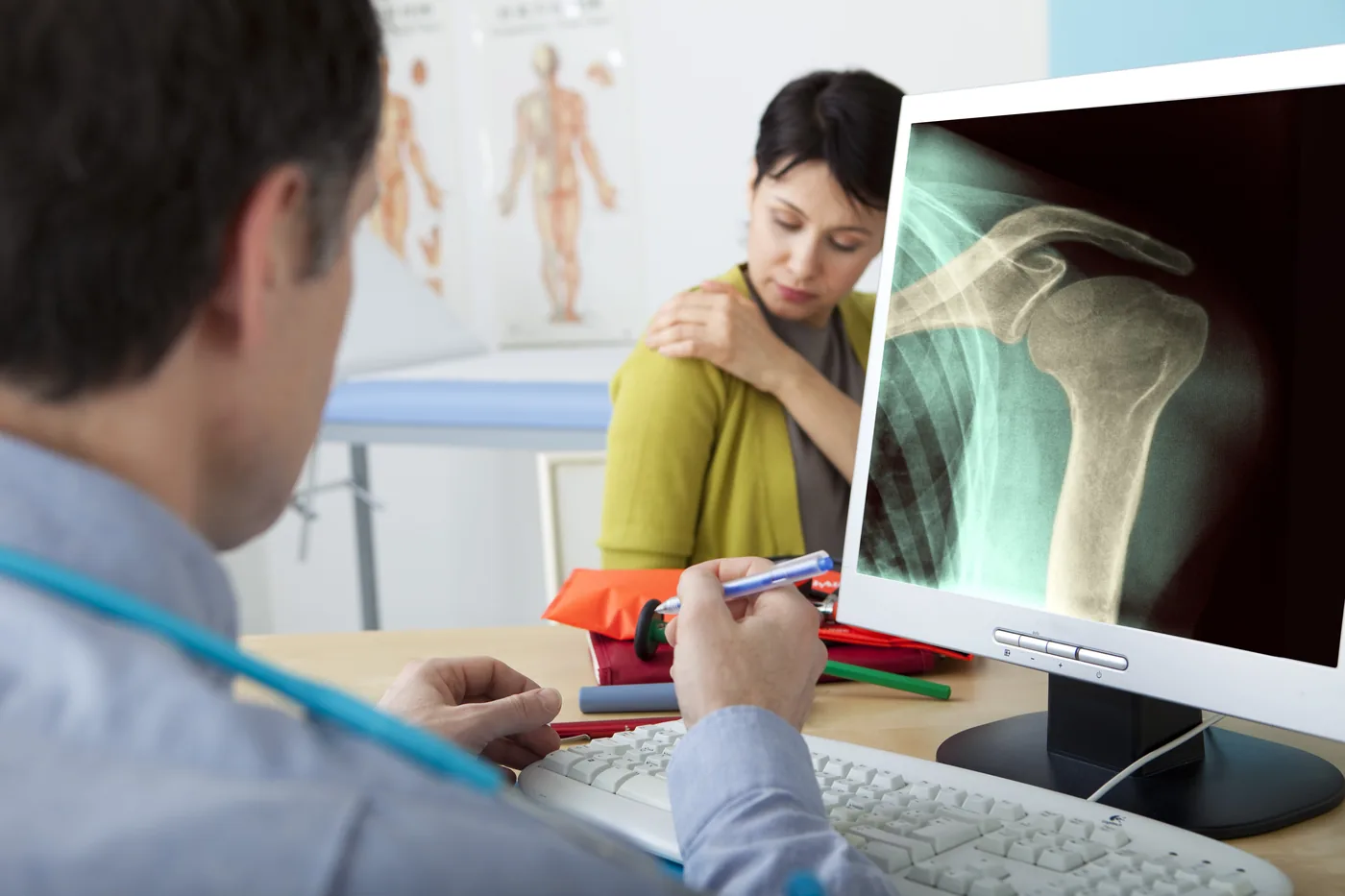 Orthopedic surgeon reviewing a shoulder X-ray with a patient during a consultation