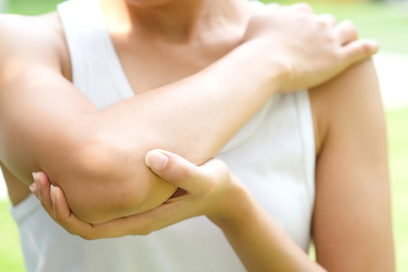 Young tennis player holding her elbow in pain